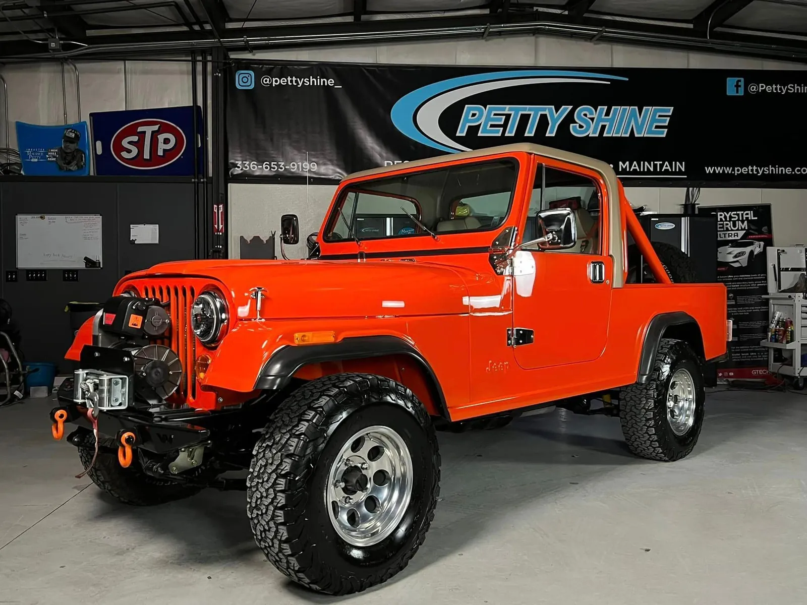 Orange Jeep on 37s inside the Petty Shine shop after a full detail