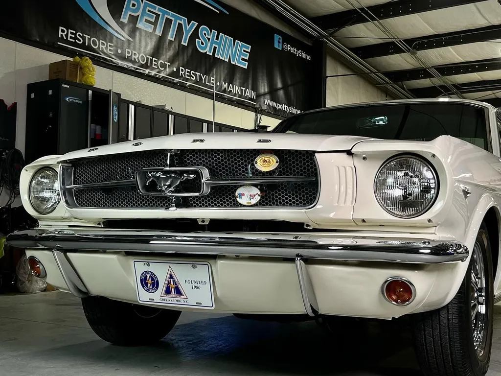 White 1965 Ford Mustang under the Petty Shine banner in the Randleman shop