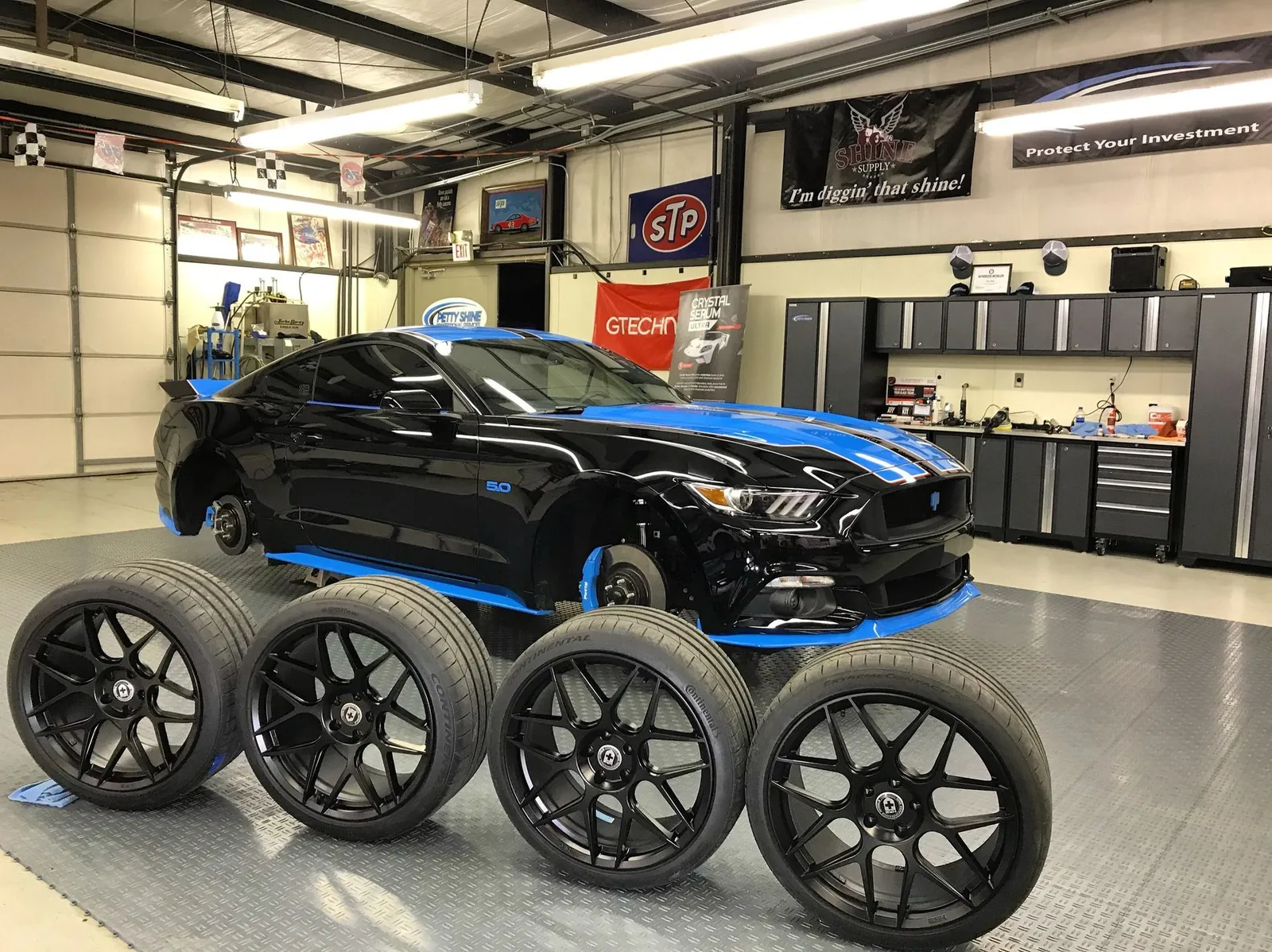 Black Ford Mustang with its wheels removed for a full wheel-off detail at Petty Shine